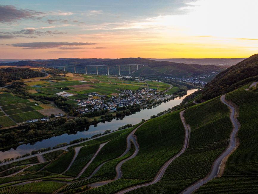 Stunning aerial view of Malroy village in Grand Est, France with vineyards and a river at sunset.